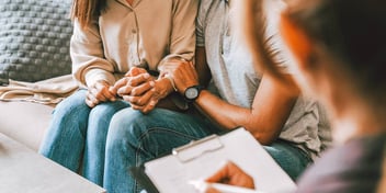 couple on couch talking while another person takes notes