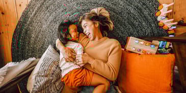 stepparent and child smiling while sharing chair