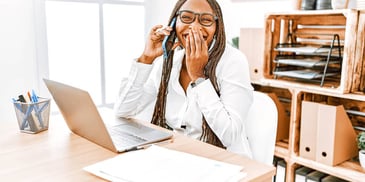 woman sitting at her computer stifling a laugh