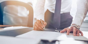 man in business attire signing a piece of divorce paperwork at a desk