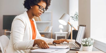 woman reviewing her financial information and paperwork on a computer